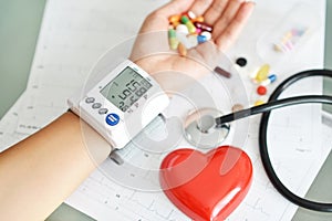 Monitoring of blood pressure of hypertensive patient, with red heart, stethoscope and pills on electrocardiogram