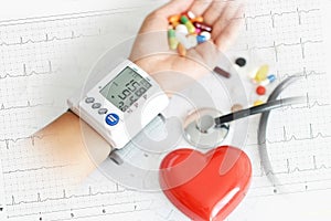 Monitoring of blood pressure of hypertensive patient, with red heart, stethoscope and pills on electrocardiogram