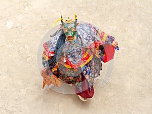 Monk in a bull deity mask with ritual dagger phurpa performs a religious masked and costumed Cham dance of Tibetan Buddhism