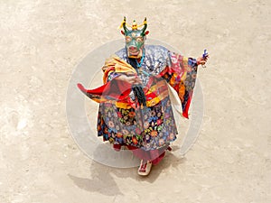 Monk in a bull deity mask with ritual dagger phurpa performs a religious masked and costumed Cham dance of Tibetan Buddhism