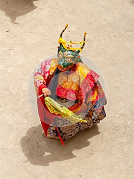 Monk in a bull deity mask with ritual dagger phurpa performs a religious masked and costumed Cham dance of Tibetan Buddhism