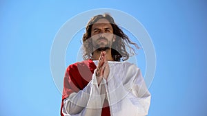 Monk praying to God against sky background, asking for blessing and forgiveness