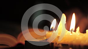 Monk reading and touching a yellow pages of old book. Close-up candle light.