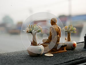 A monk statue being placed on a driving car dashboard in Thailand as the Thais believe that the statue save them from road acciden