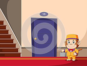 The monkey as the bell boy holding the grey suite case standing in front of the hotel`s door