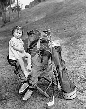 Monkey with golf clubs and toddler girl photo