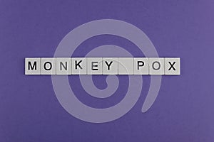 MONKEY POX. Word written on square wooden tiles on purple background. Viral disease. photo