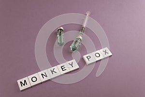MONKEY POX. Words written on square wooden tiles with vaccine on pink background. photo