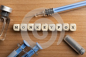 Monkeypox pandemic concept: dice surrounded by syringes and vials make up the word monkeypox