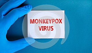 Monkeypox virus symbol. Concept words Monkeypox virus on white card. Doctor hand in blue glove with white card. Medical and