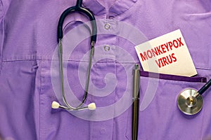 Monkeypox virus symbol. Medical uniform, white card with concept words Monkeypox virus, metalic pen and stethoscope. Medical and photo