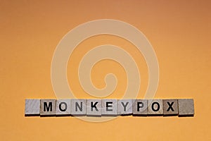 MONKEYPOX. Word written on square wooden tiles with an orange background. Monkeypox is a zoonotic viral disease photo