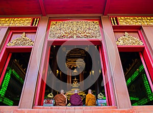 Monks with three colors robe pay respect to emerald Buddha sculpture at Wat Phra Kaeo - Chiang Rai, Thailand