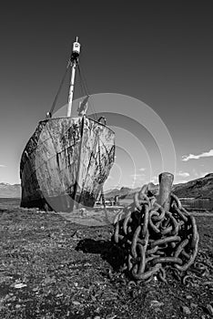 Mono whaler with harpoon beside rusty chain photo