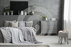 Monochromatic grey bedroom interior with a big bed with throws a