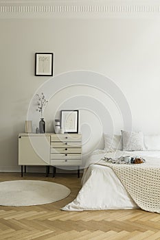 Monochromatic, white bedroom interior with a bed and a nightstand. Breakfast served on the bed. Real photo.