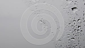 Monochrome background of wet glass with dripping droplets and copy space