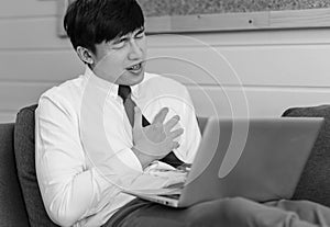 Monochrome black and white shot of unrecognizable unknown male businessman employee in formal business outfit sitting on cozy sofa