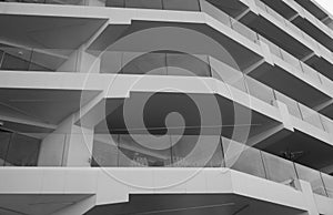 Monochrome detail shot of a facade of a skyscraper. You can see surrounding balconies and large glass windows