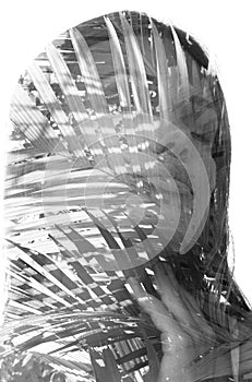 A monochrome double exposure portrait of a woman with palm leaves on white background