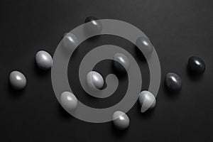 Monochrome gradient Easter eggs lie in a row on a black background, top view