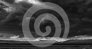 Monochrome image, dramatic storm clouds over empty agricultural fields