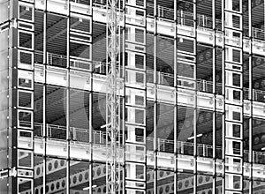 Monochrome image of a large construction site with steel framework and girders with fences and building hoist