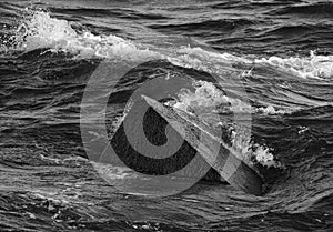 Monochrome image of large textured concrete structure of pier in sea water