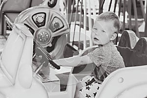 Monochrome image of little boy driving toy child car