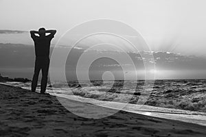 Monochrome image of man at sunrise on beach