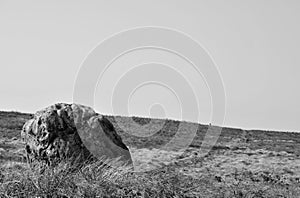 Monochrome image of a pennine landscape with large old boulder or standing stone on midgley moor in west yorkshire