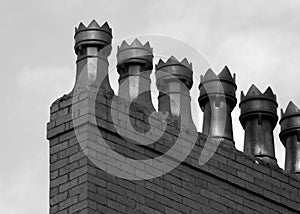 Monochrome image of a row old fashioned chimney pots on a brick built house