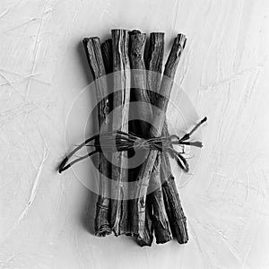 Monochrome image of a stack of wooden twigs on a wooden surface, AI-generated.