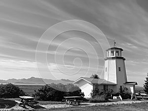 Monochrome of a light house in Homer, Alaska with trees and benches around