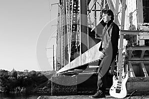 Monochrome man with an electric guitar in the industrial landsca