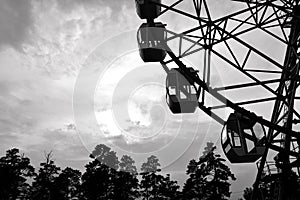 Monochrome photo. Big wheel in the city park at sunset. Rest in the amusement park