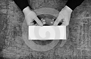 Monochrome photo male hands holding a white blank sheet of paper