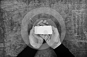 Monochrome photo male hands holding a white blank sheet of paper