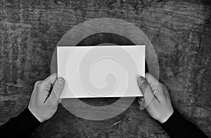 Monochrome photo male hands holding a white blank sheet of paper