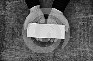 Monochrome photo male hands holding a white blank sheet of paper