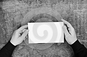 Monochrome photo male hands holding a white blank sheet of paper