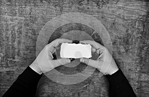 Monochrome photo male hands holding a white blank sheet of paper