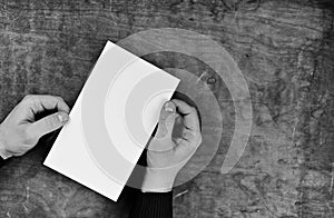 Monochrome photo male hands holding a white blank sheet of paper