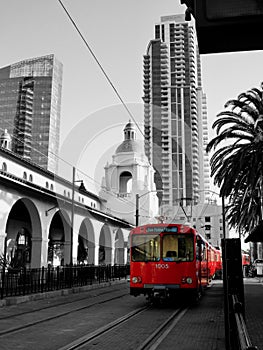 Monochrome photo with red San Diego trolley, outside the rail station.