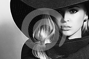 Monochrome portrait of Beautiful Blond Woman in Black Hat. Fashionable Lady in Topcoat
