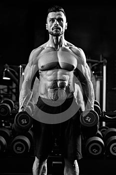 Monochrome portrait of bodybuilder holding dumbbells.