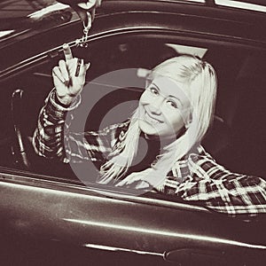 Monochrome portrait of smiling young woman receiving car keys to used car