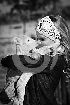 Monochrome portrait of woman cuddling little lamb