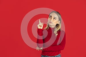 Monochrome portrait of young caucasian blonde woman on red background