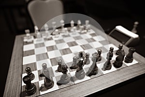 Monochrome shallow depth of field selective focus image with wooden chess pieces on a wooden table before a professional